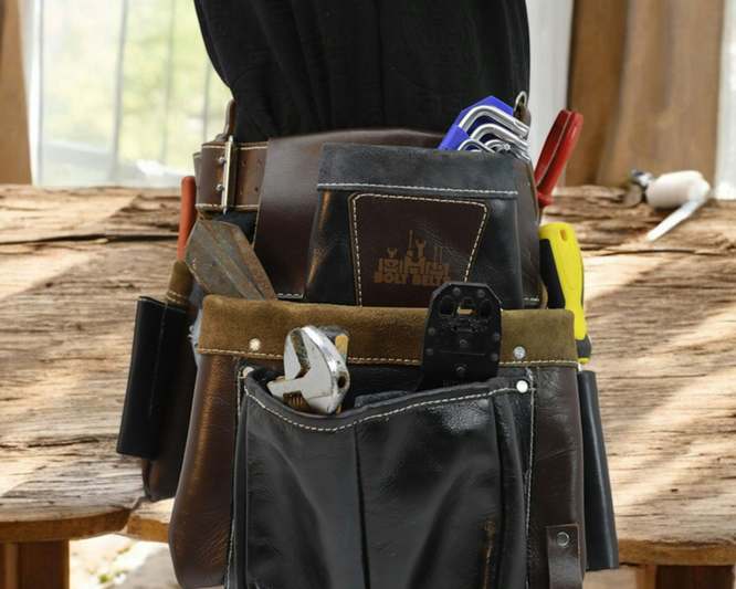 Side-by-side comparison of five tool belts laid out on a workshop bench with calipers, torque wrench, and notebook showing handwritten notes